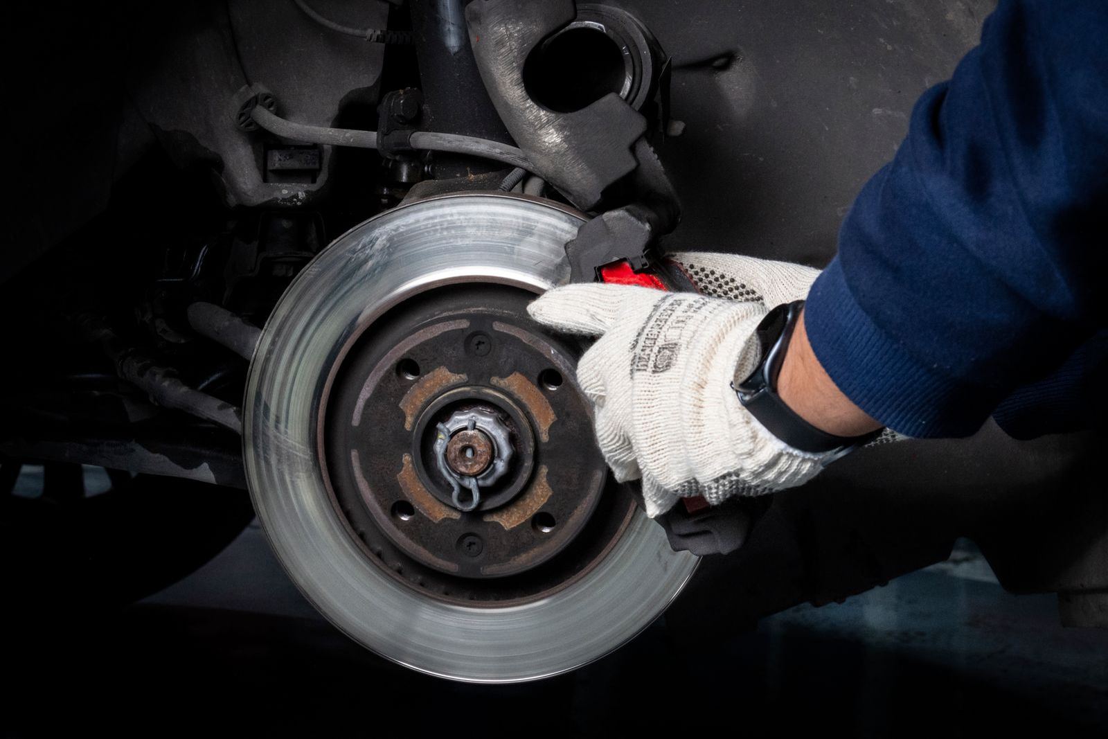 Stock photo: a gloved hand holding a brake rotor on a hub with the wheel removed.