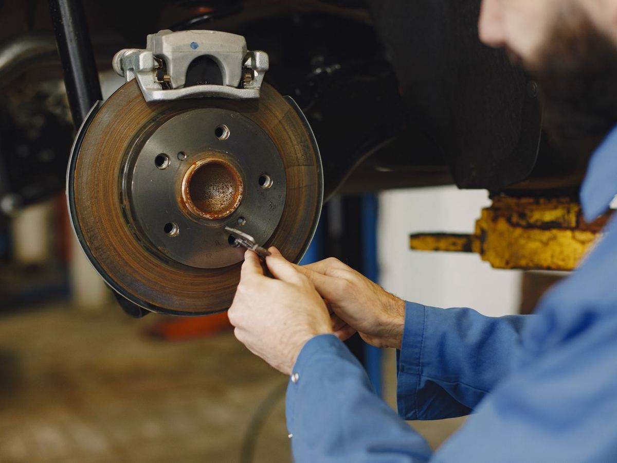 Stock photo: a mechanic's hand on a brake rotor and caliper with the wheel removed.