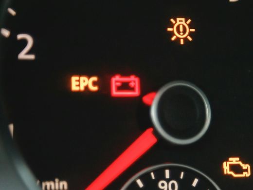 Close-up of a lit battery warning symbol on a dashboard. Stock photo.