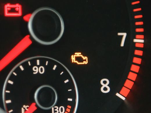 Close-up of a lit check engine symbol on a dashboard. Stock photo.