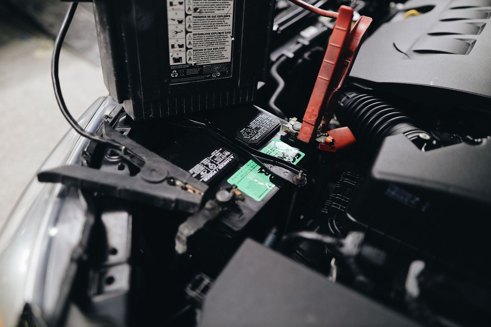 Jumper clamps attached to the terminals of a car battery. Stock photograph.