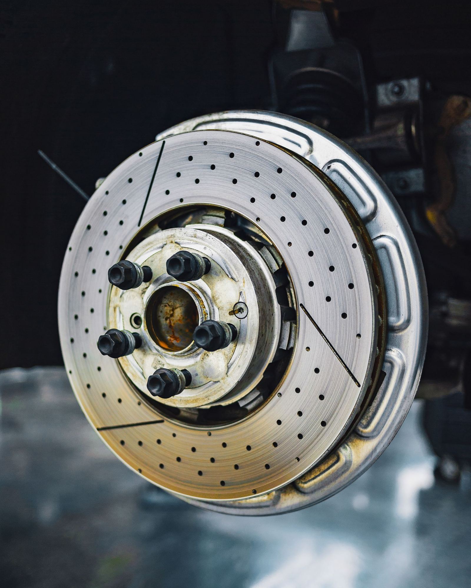 A drilled and slotted brake rotor photographed against a dark background. Stock photograph.